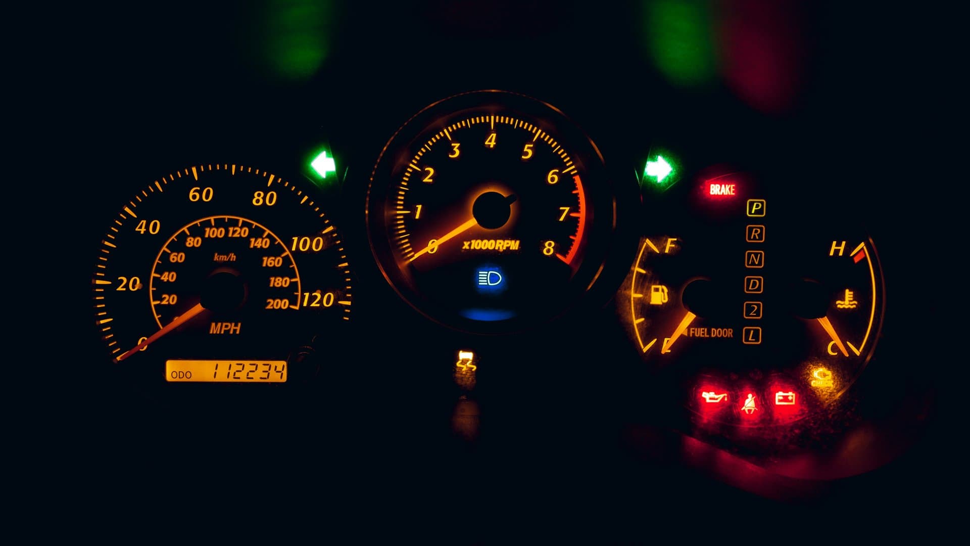 Close-up of a car dashboard at night with several illuminated warning light icons glowing on the instrument cluster